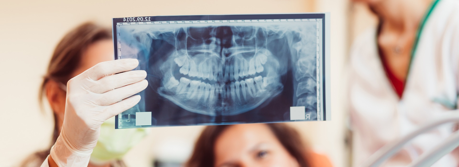 Patient schaut sich mit Zahnärzten ein Röntgenbild ihrer Zähne an