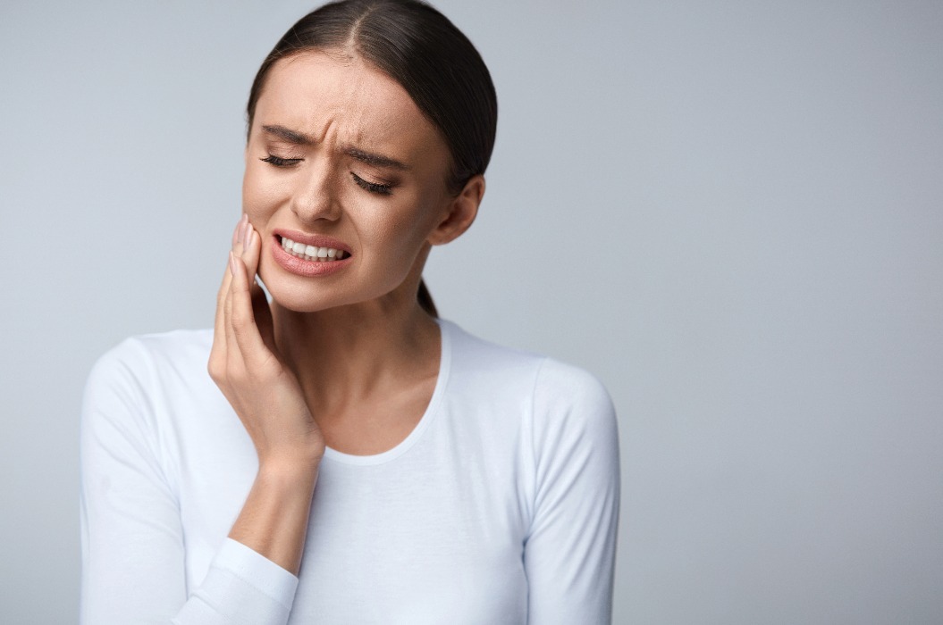 Frau hält sich Wange wegen Zahnschmerzen, als Symbol für die Endodontie