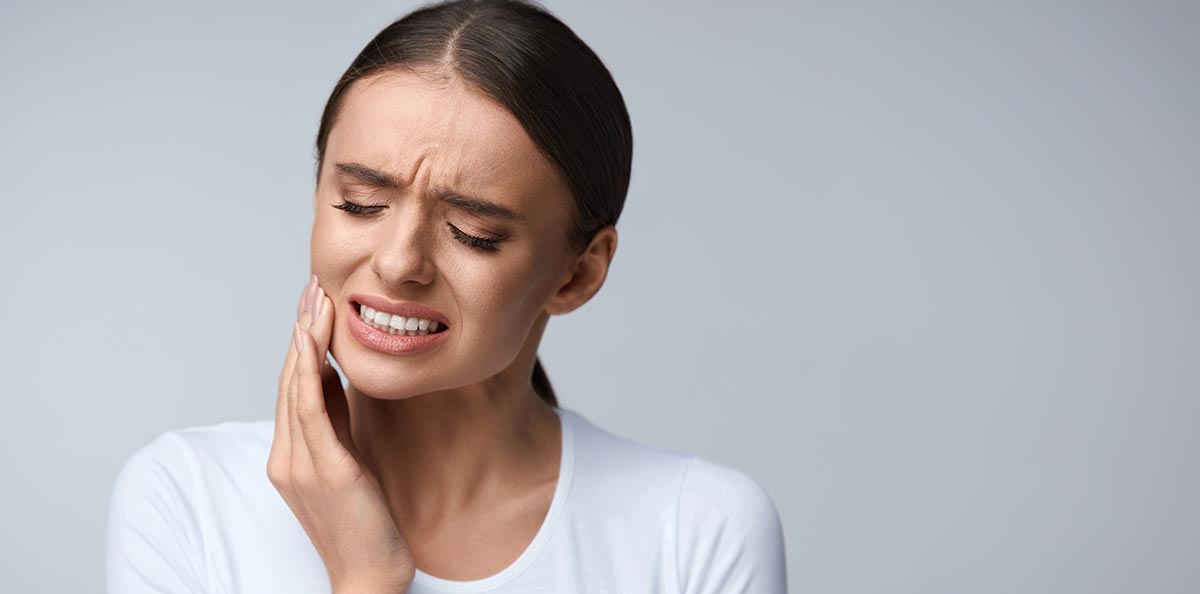Frau hält sich Wange wegen Zahnschmerzen, als Symbol für die Endodontie
