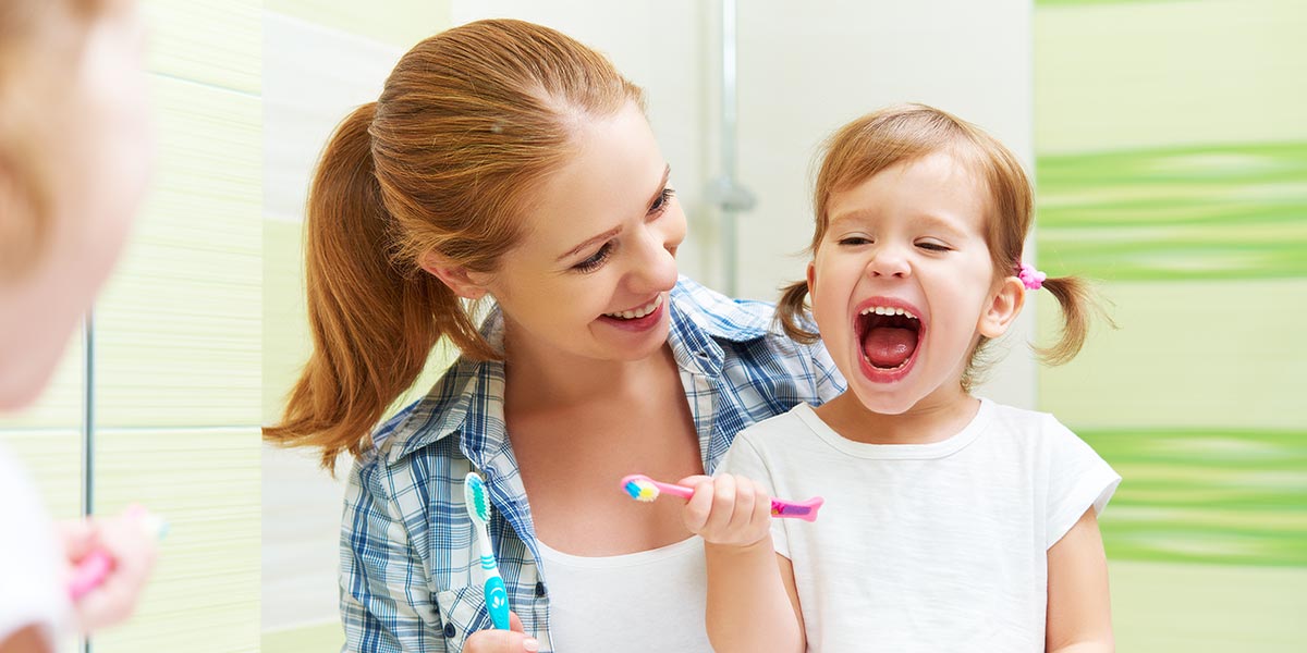Mutter zeigt kleinen Tochter wie man Zähne putzt